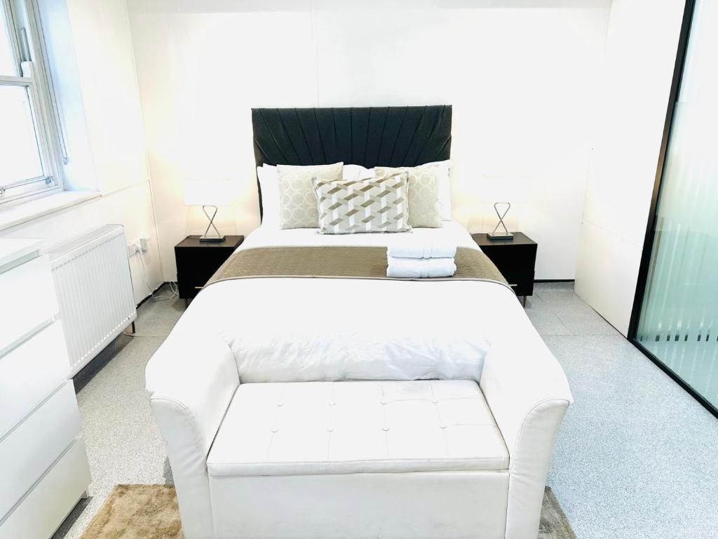 a bedroom with a large white bed with a bench at Westferry Two-Bedroom Deluxe Apartment in London
