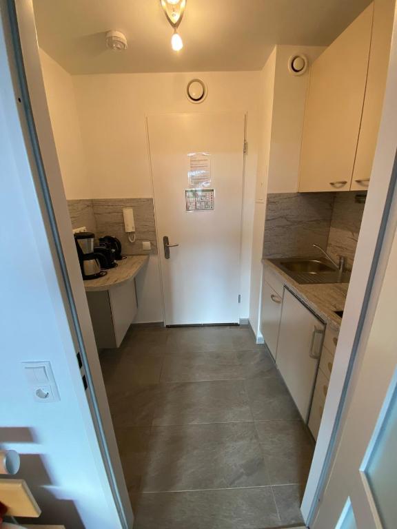 a small kitchen with white cabinets and a door at Panoramalounge 712 in Lahnstein