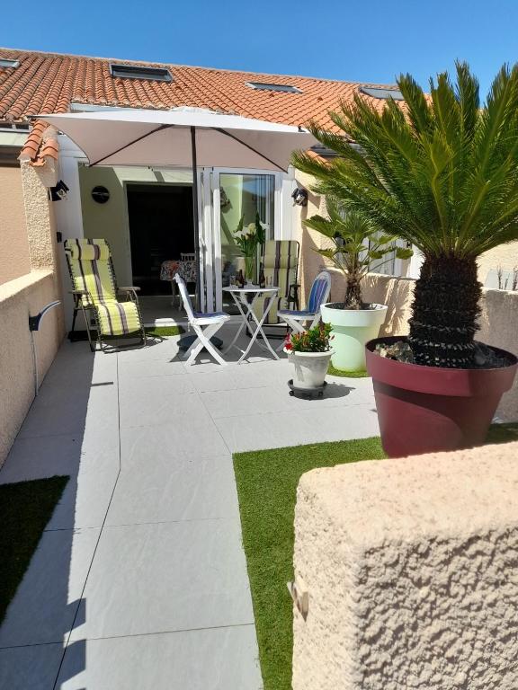 Cette maison dispose d'une terrasse avec des chaises et un parasol. dans l'établissement Maison Les Sables D'olonne, à Les Sables-dʼOlonne