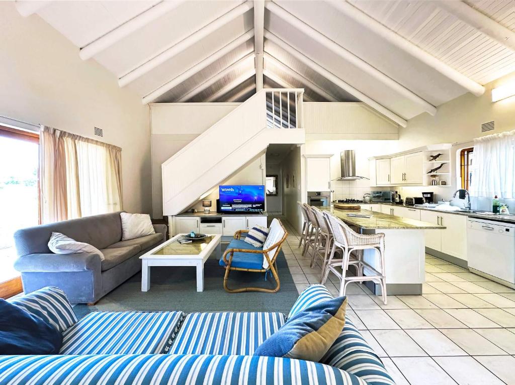un soggiorno con divano e cucina di Chalet 40 Plettenberg Bay A tranquil location with beach access in large grounds ideal for families a Plettenberg Bay