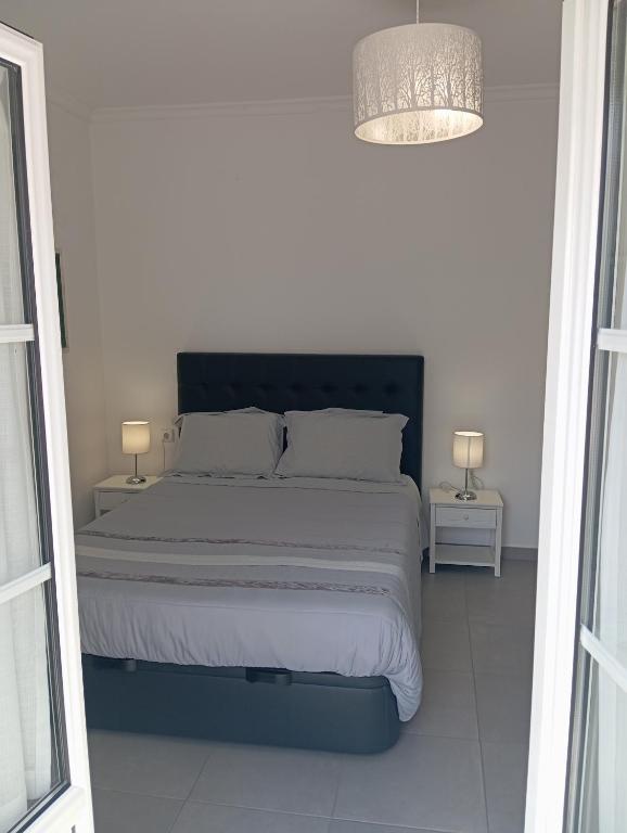 a white bedroom with a large bed with two lamps at Casa do Sol - 70 m from the beach in Nazaré