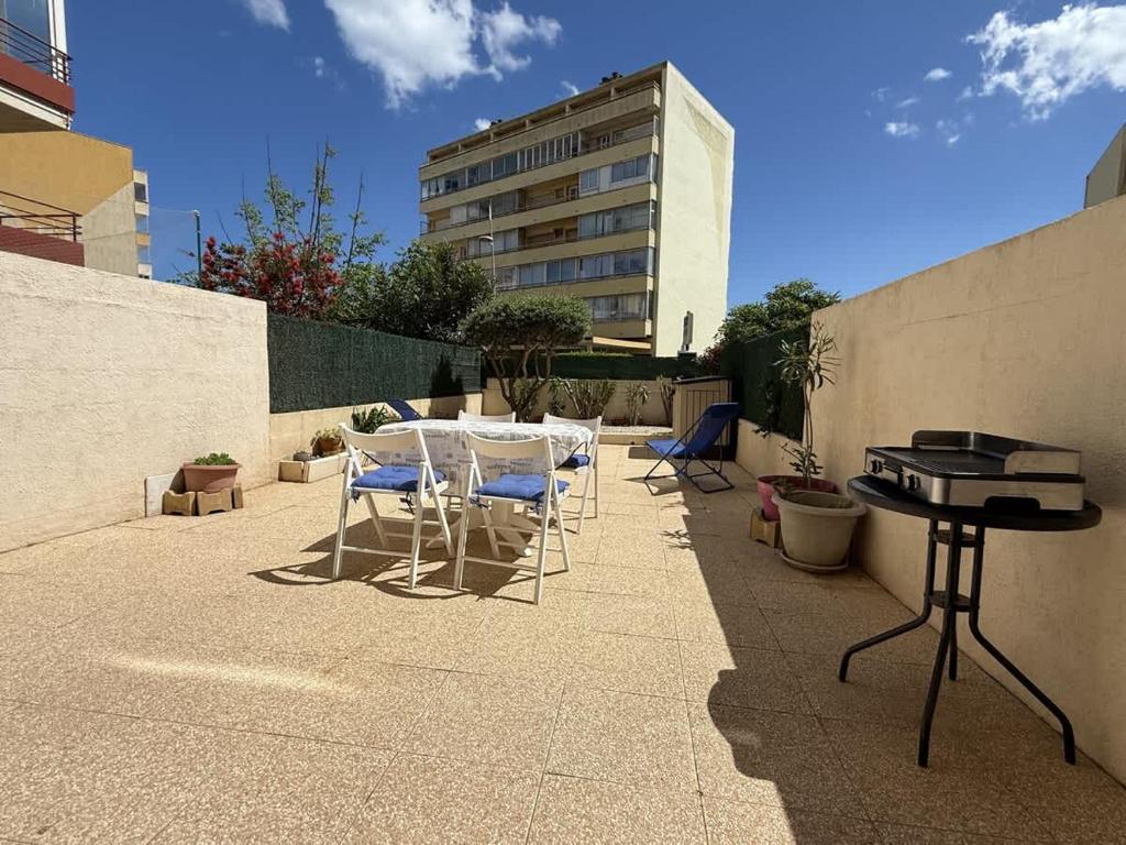 un patio avec des chaises, une table et un grill dans l'établissement Valras'Loc Cap Horn, à Valras-Plage