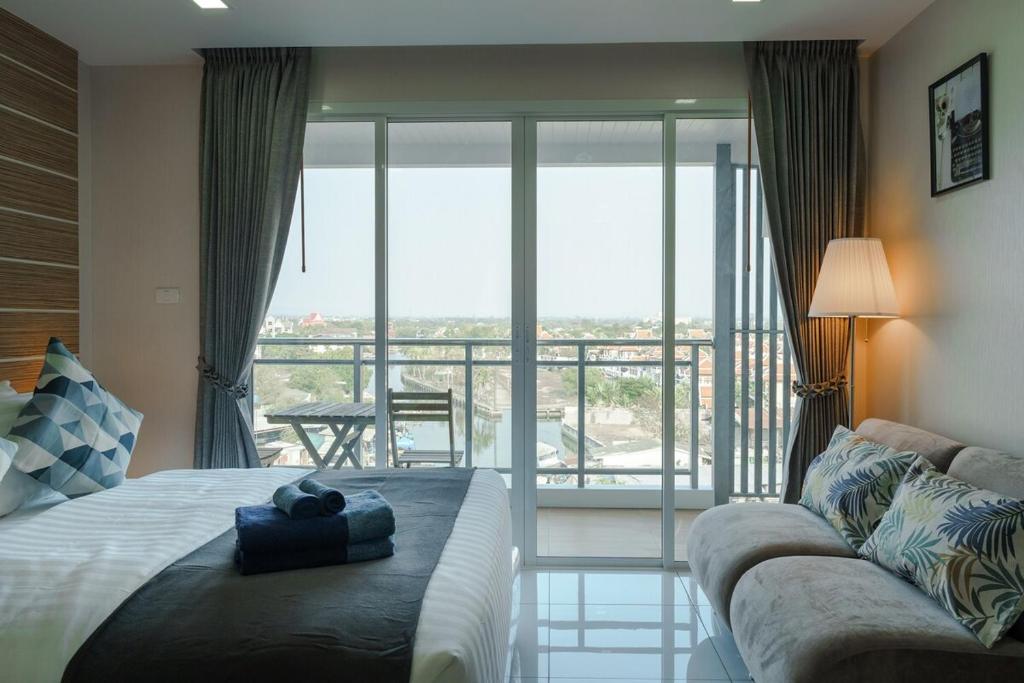 a bedroom with a bed and a couch and a balcony at NEW amazing studio a private marina in Na Jomtien