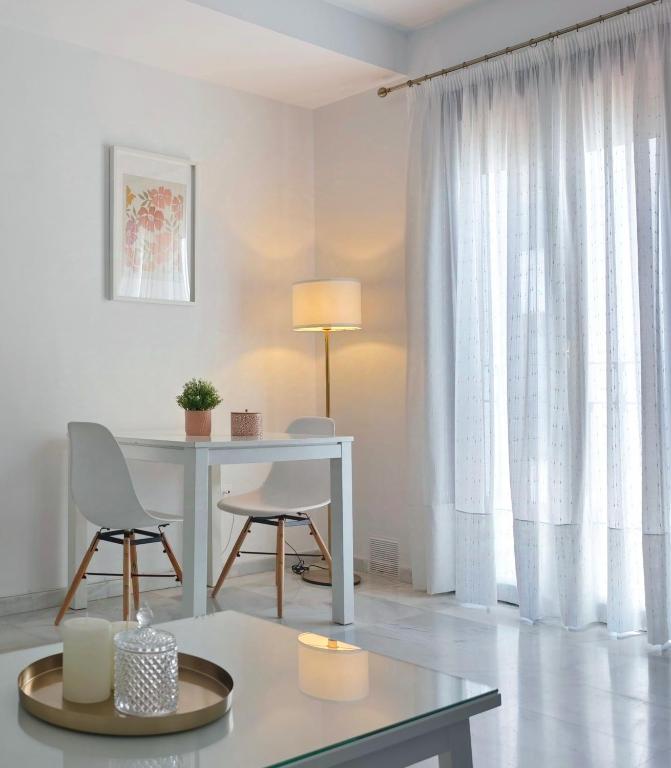 a white living room with a table and chairs at Living Sevilla & Parking gratis in Seville