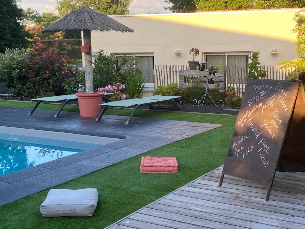 een achtertuin met een zwembad en een tafel met een parasol bij La Casa d'Audenge in Audenge