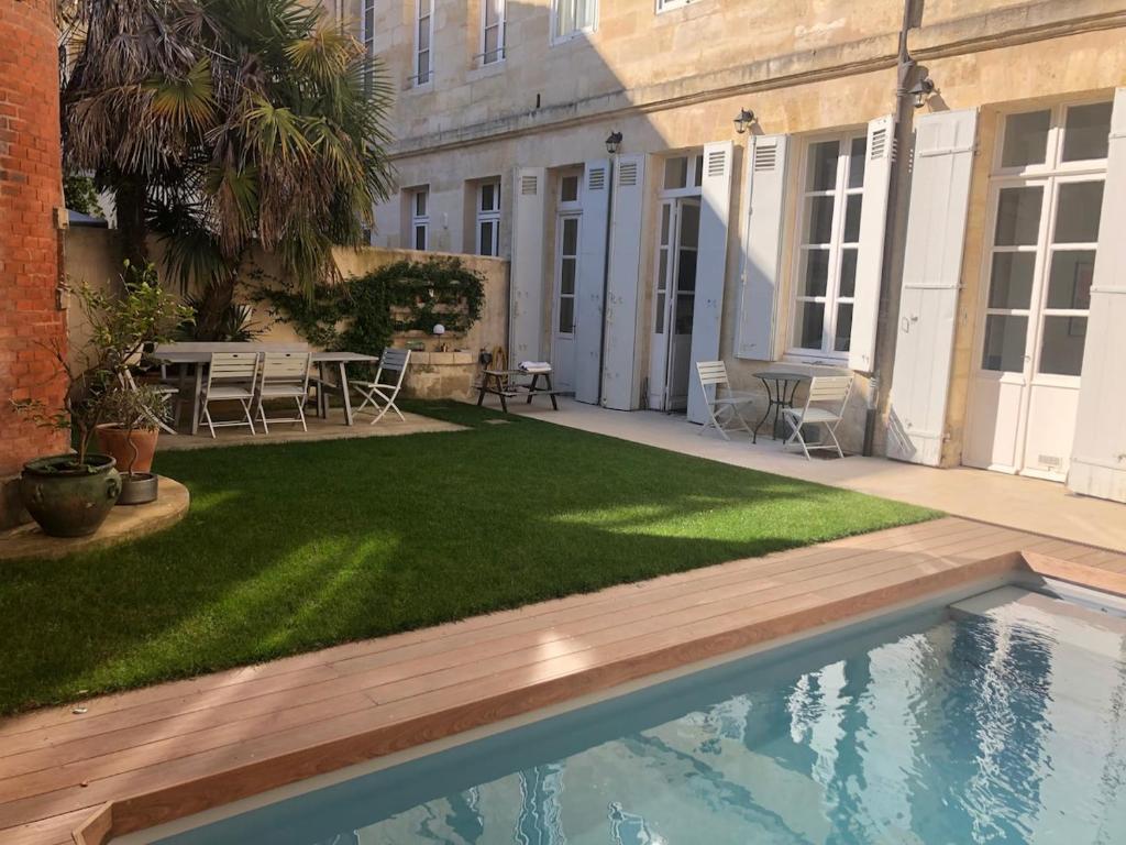 une cour avec une pelouse et une piscine dans l'établissement Maison en centre ville avec jardin et piscine, à Bordeaux