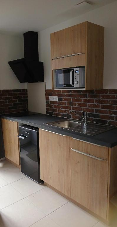 une cuisine avec un évier et un micro-ondes dans l'établissement Gîte du Roc 2, à Les Portes du Coglais