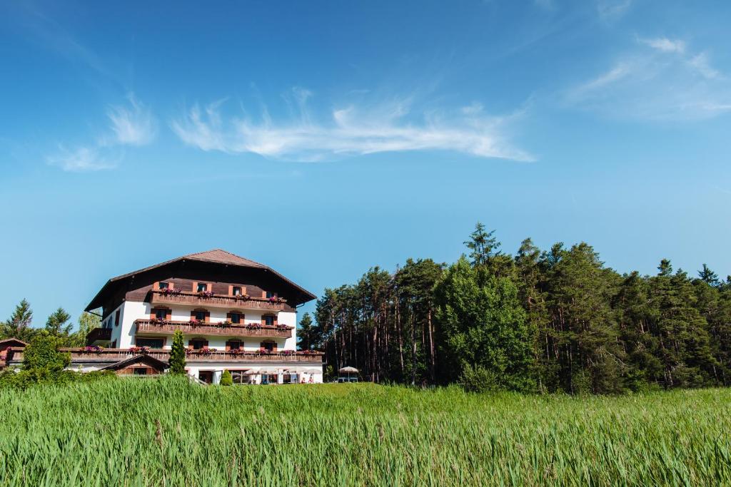 a large house on a hill in a field at Hotel Waldsee in Völs am Schlern