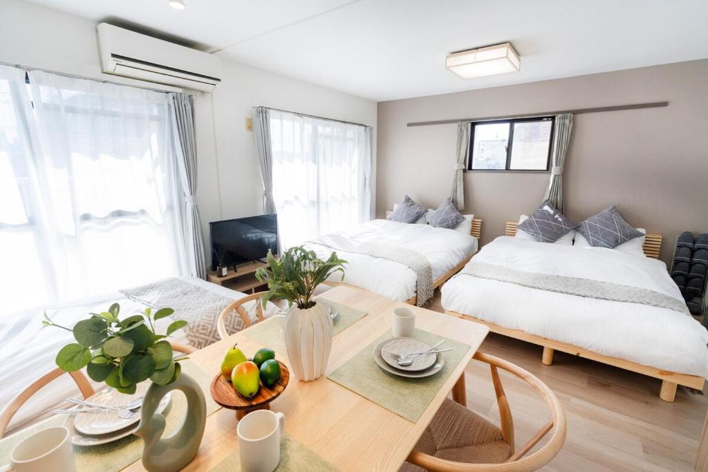 a room with two beds and a table with a dining room at Alpha memory NAGOYA in Mutsunochō