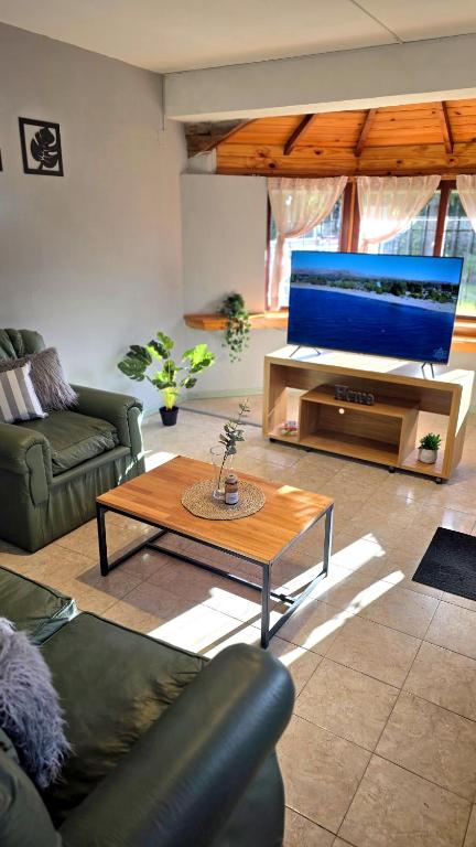 a living room with a television and a coffee table at Rincon de la Araucaria Dina Huapi in Dina Huapi