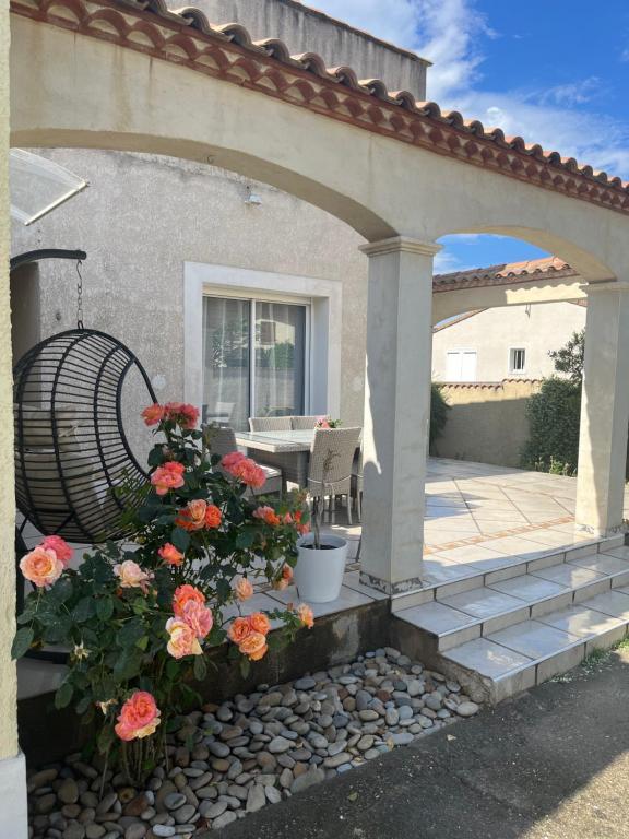 un patio avec des fleurs et une arche avec une table dans l'établissement L'Ostal de Jacou, à Jacou