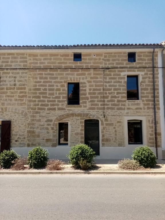 un bâtiment en briques avec des fenêtres et des buissons devant dans l'établissement passage 1, à Montaren-et-Saint-Médiers
