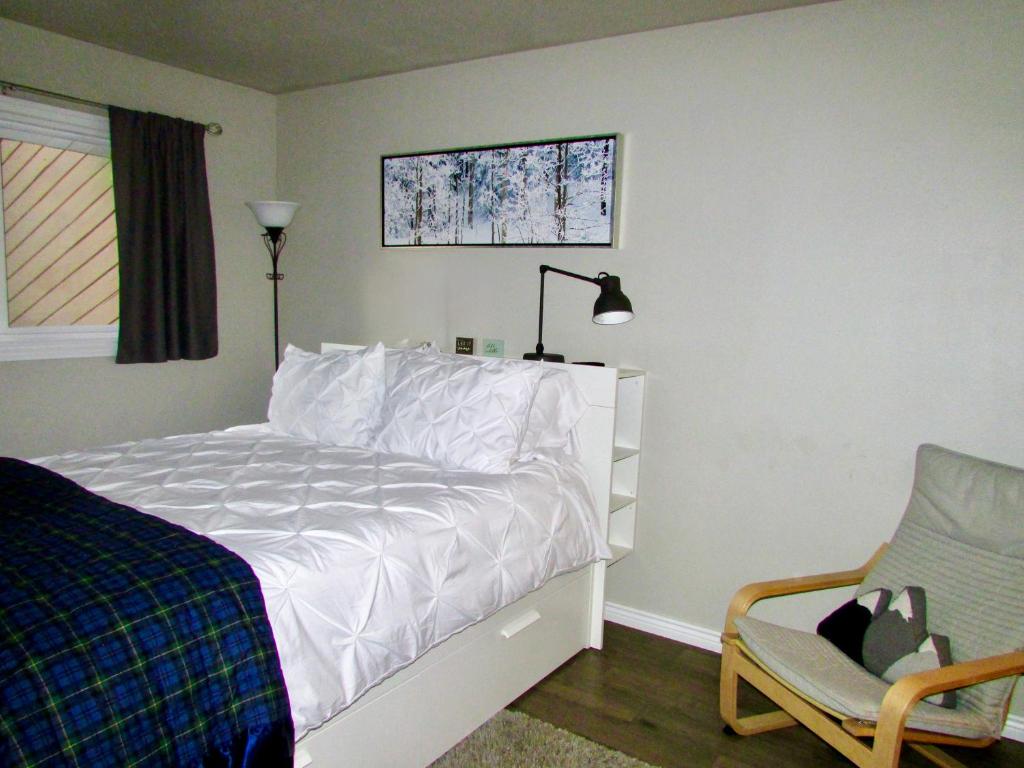 a bedroom with a white bed and a chair at Renovated condo steps from Beaver Creek shuttle in Avon