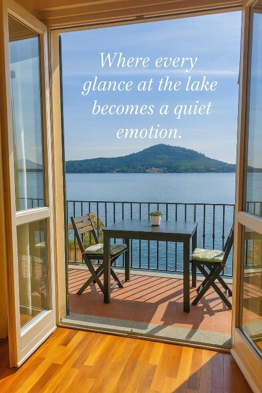 a window with a table and chairs on a balcony at Scarlet Flower - Lago Maggiore in Meina