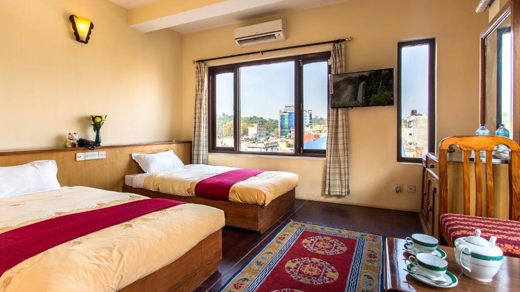 a hotel room with two beds and a window at Hotel Khumbila in Kathmandu