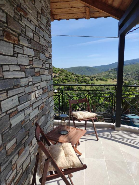 a patio with two chairs and a table on a stone wall at Ανέμη in Panayía