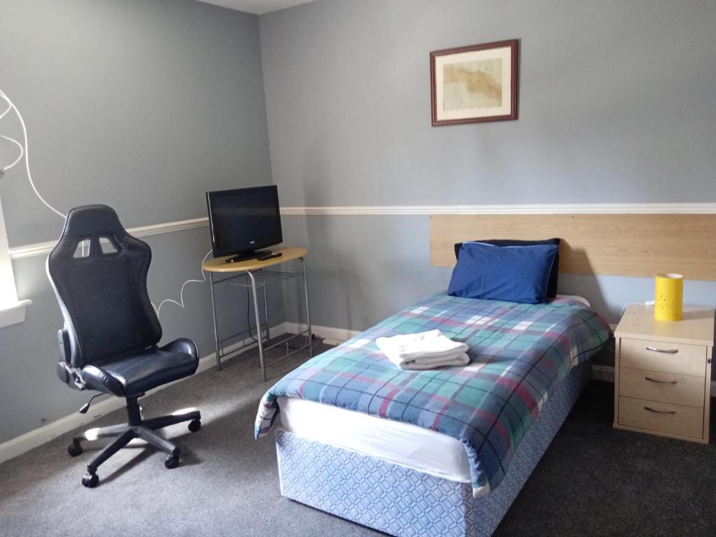 a bedroom with a bed and a chair and a desk at Pokój 1osobowy in Moffat