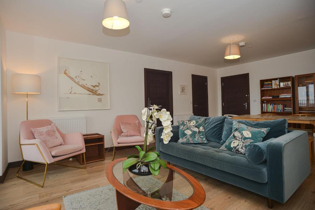 a living room with a blue couch and two chairs at Seaview City Lodge , 2- bedroom flat with Parking in Southend-on-Sea