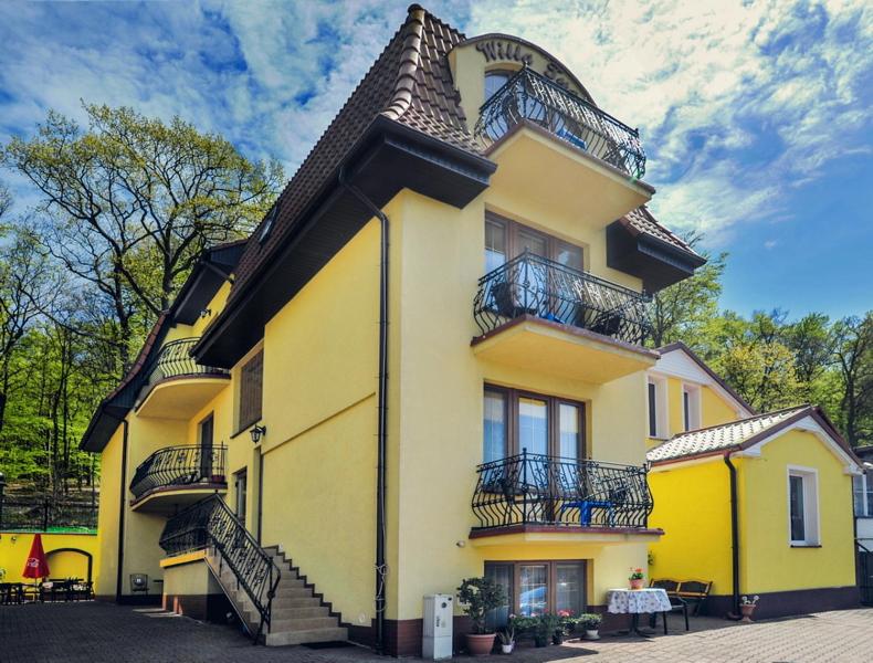 żółty budynek ze schodami i balkonami w obiekcie Willa Tusia w mieście Międzyzdroje
