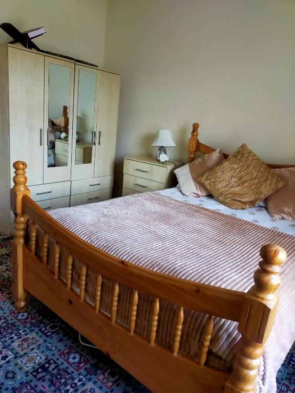 a bedroom with a wooden bed with a dresser and a mirror at Newly Decorated Spacious room, Women only in Bradford