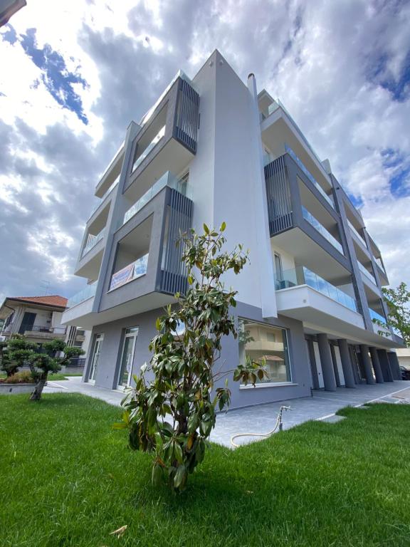 Un edificio blanco con un árbol delante. en Santa Fe Rooftop Luxury Apartments, en Tortoreto Lido