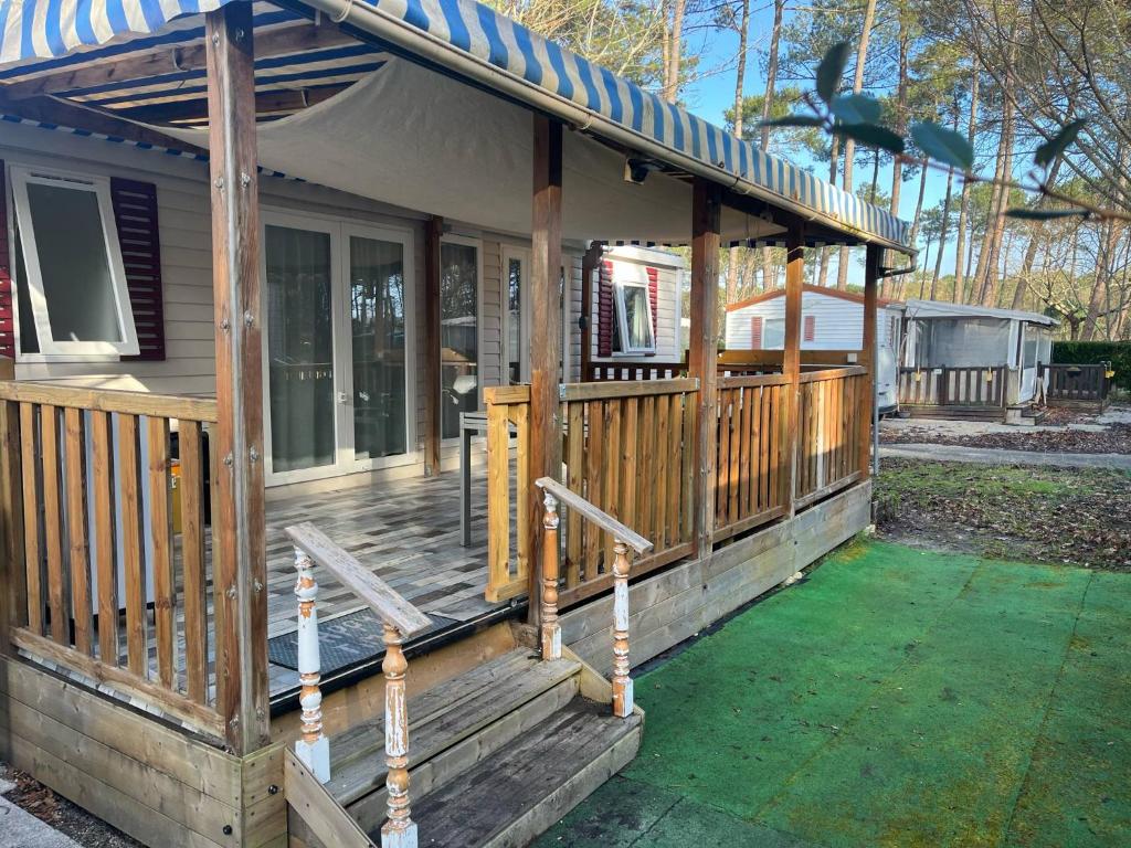 une maison avec une terrasse couverte en bois et un toit dans l'établissement Mobil-home, à Bias