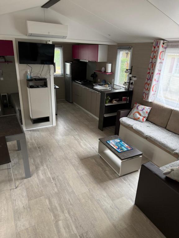 un salon avec un canapé et une cuisine dans l'établissement Mh rideau, à La Tremblade