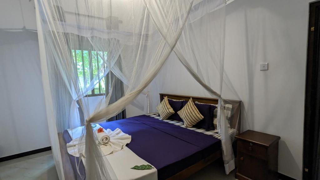 a bedroom with a canopy bed with blue sheets and pillows at Galhena Villa in Tangalle