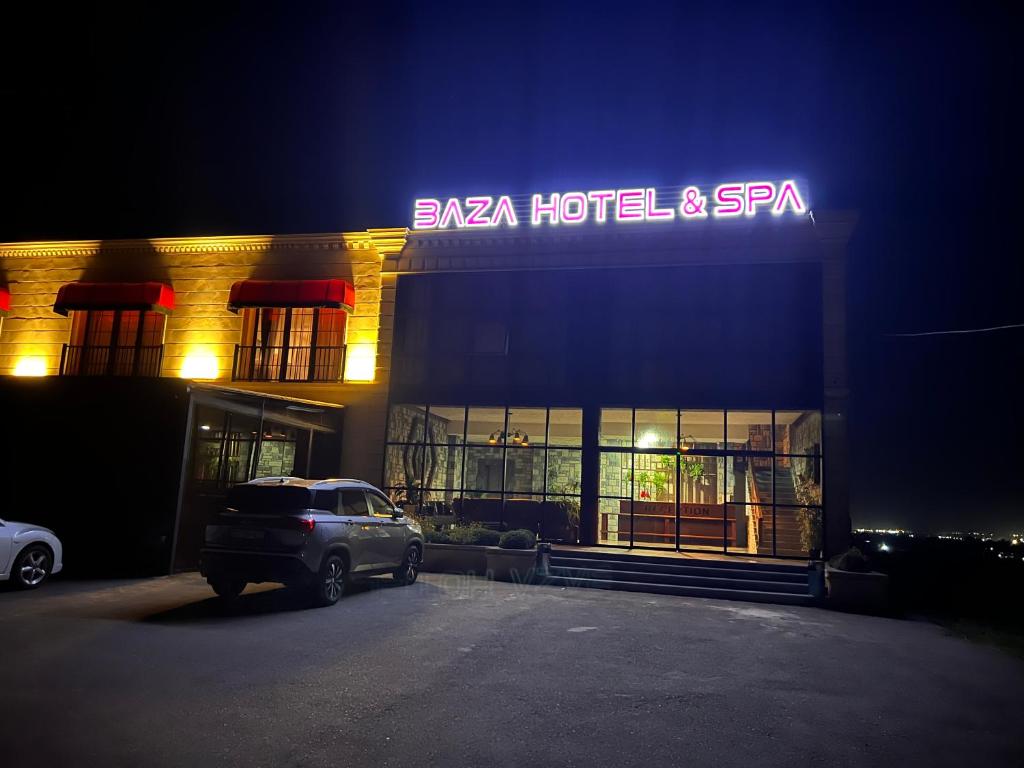 a building with a car parked in a parking lot at Baza Hotel Spa in Beylǝqan