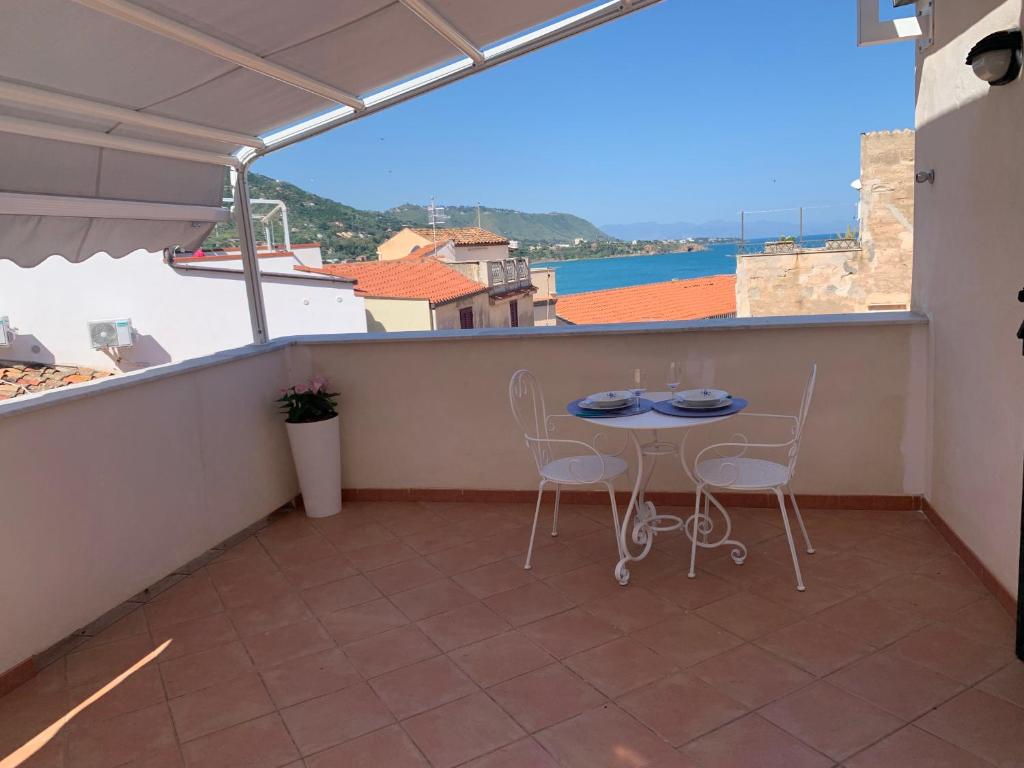 a balcony with a table and chairs and a view of the ocean at La vista al di sopra dei tetti in Cefalù