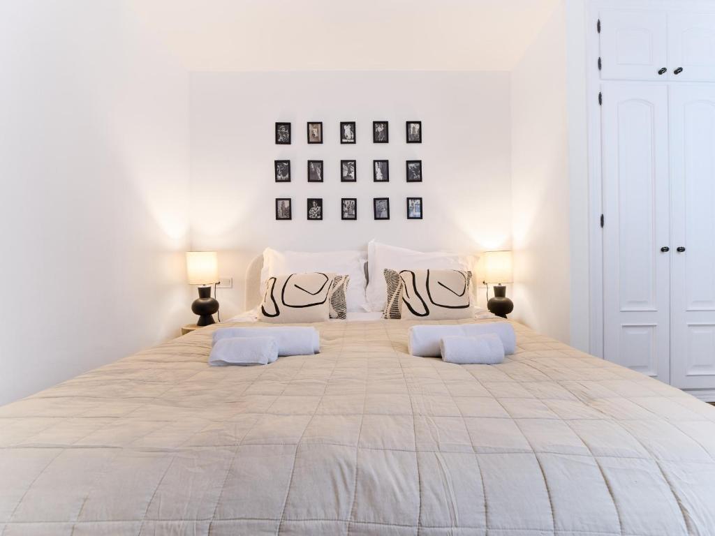 a white bedroom with a large bed with two pillows at Casa Wanda in Estepona