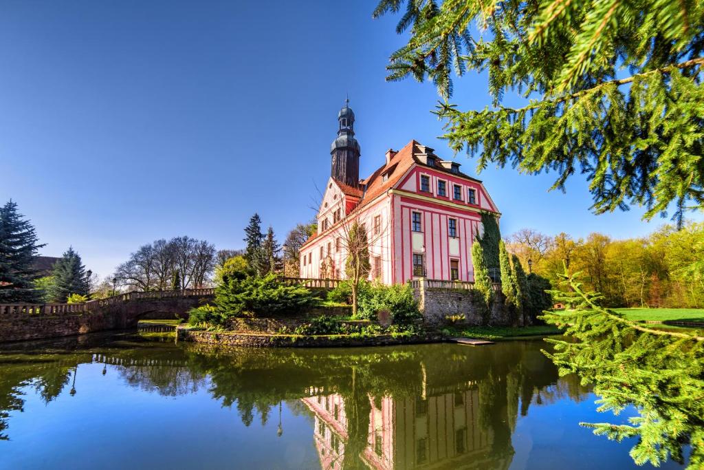 uma casa velha com um lago em frente em Boutique Pałac Warmątowice Sienkiewiczowskie em Legnica