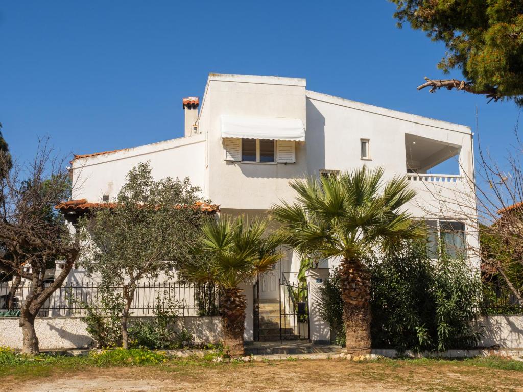 a white house with palm trees in front of it at St Nickolas Guest House in Artemida
