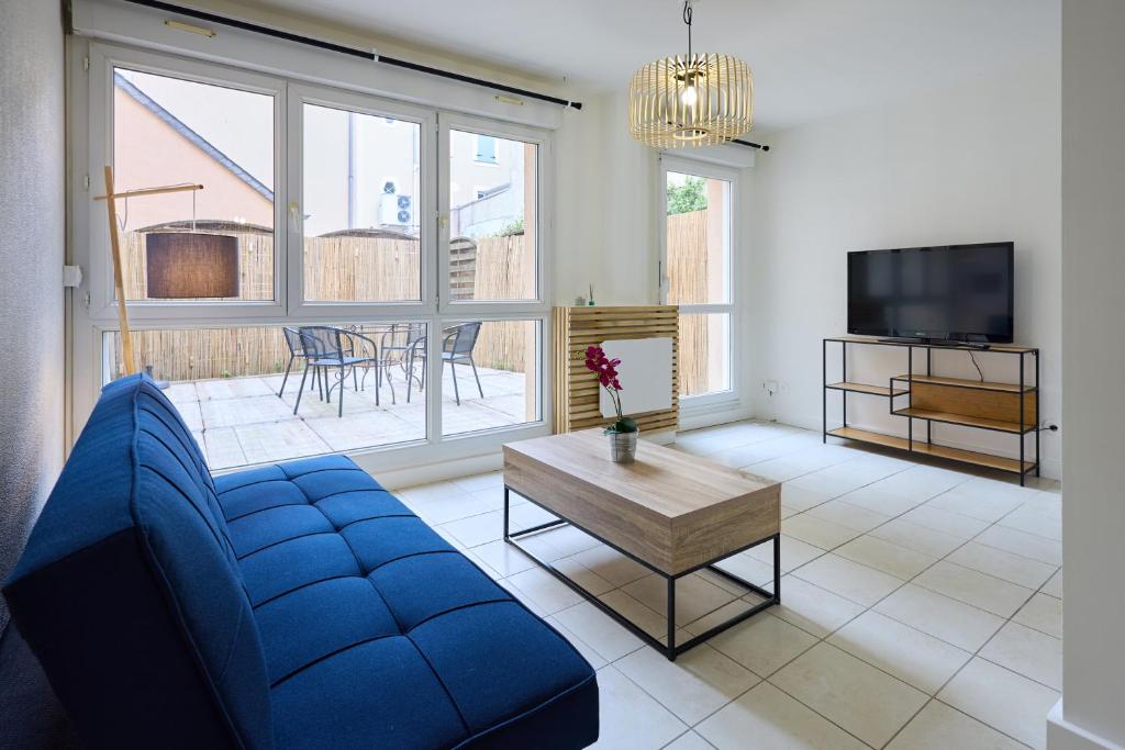 a living room with a blue couch and a tv at La Terrasse du Bonheur in Le Mans