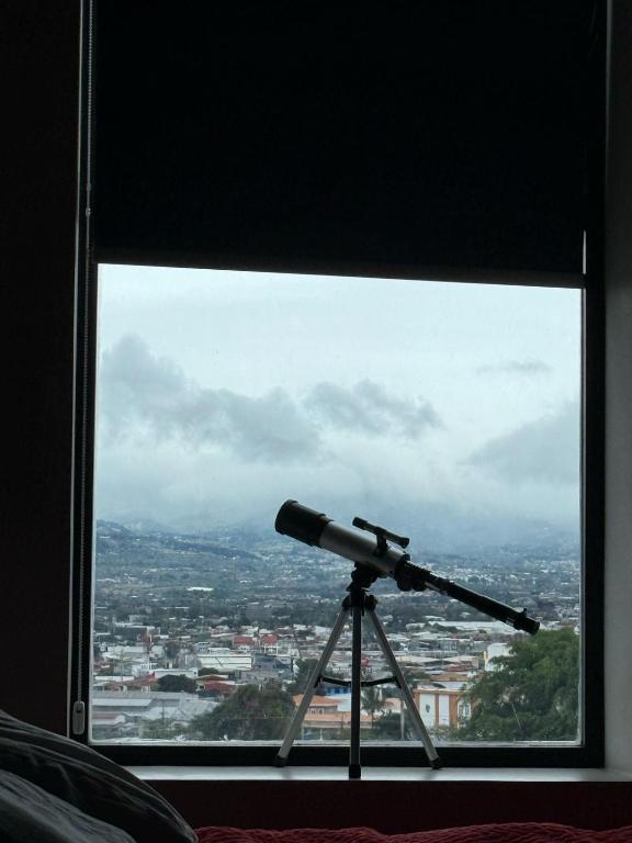a telescope looking out a window at a city at Apartamento Vista 11 URBN Escalante in San José