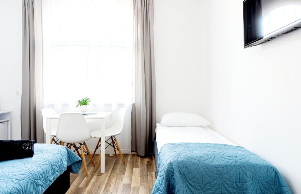 a bedroom with two beds and a table and a window at Przy Plaży in Karwia