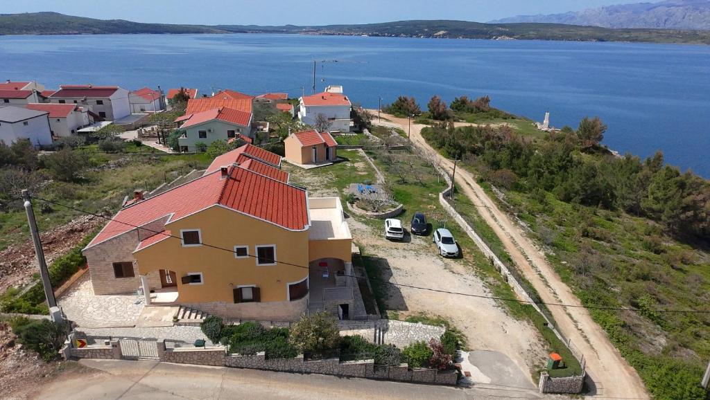 a house with a red roof on a hill next to the water at Apartments Mikecin in Novigrad Dalmatia