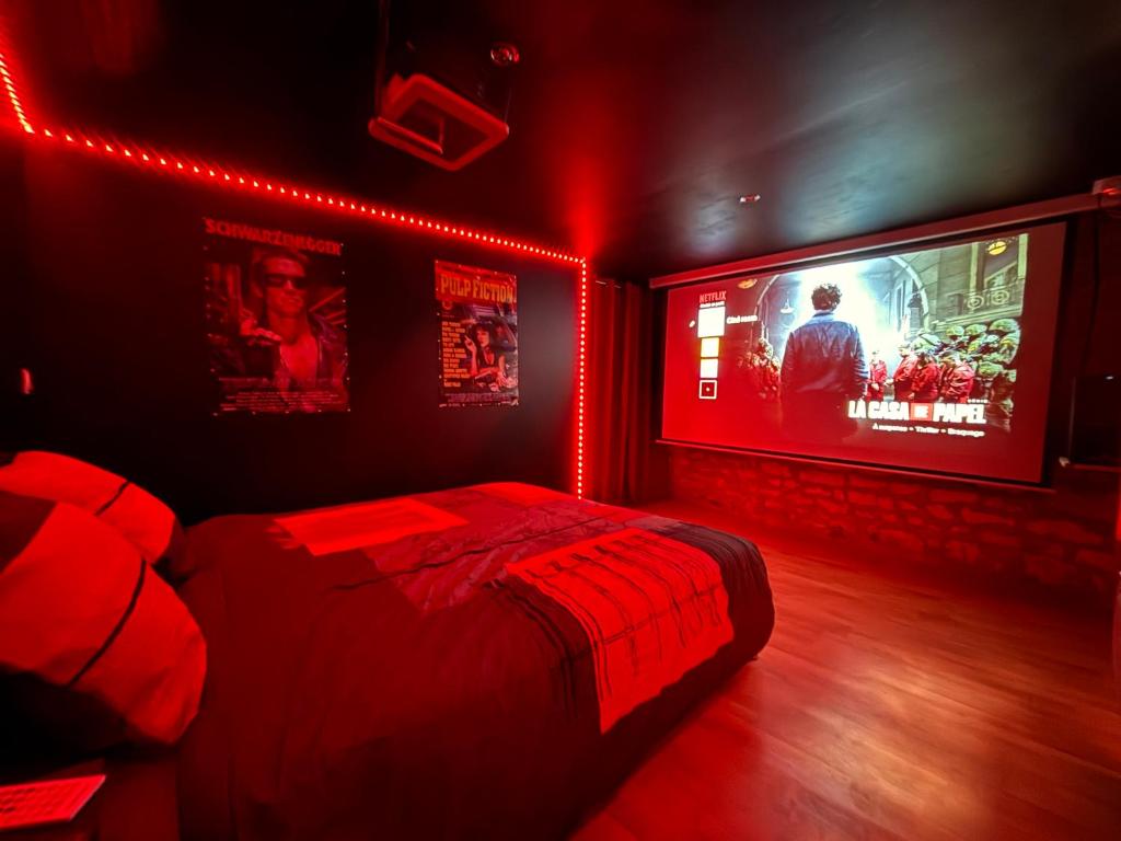 a bedroom with a bed and a tv with red lights at Cinema room - Proche Auxerre in Vincelles