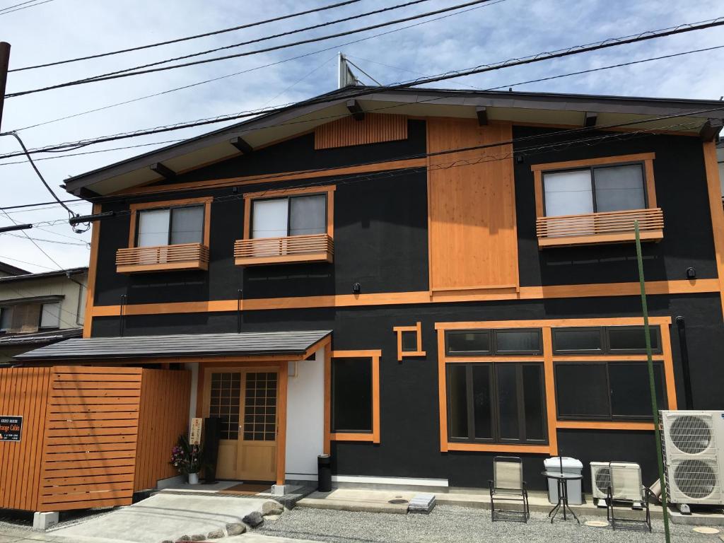 uma casa preta e laranja com cadeiras em frente em GuestHouse OC em Fujikawaguchiko