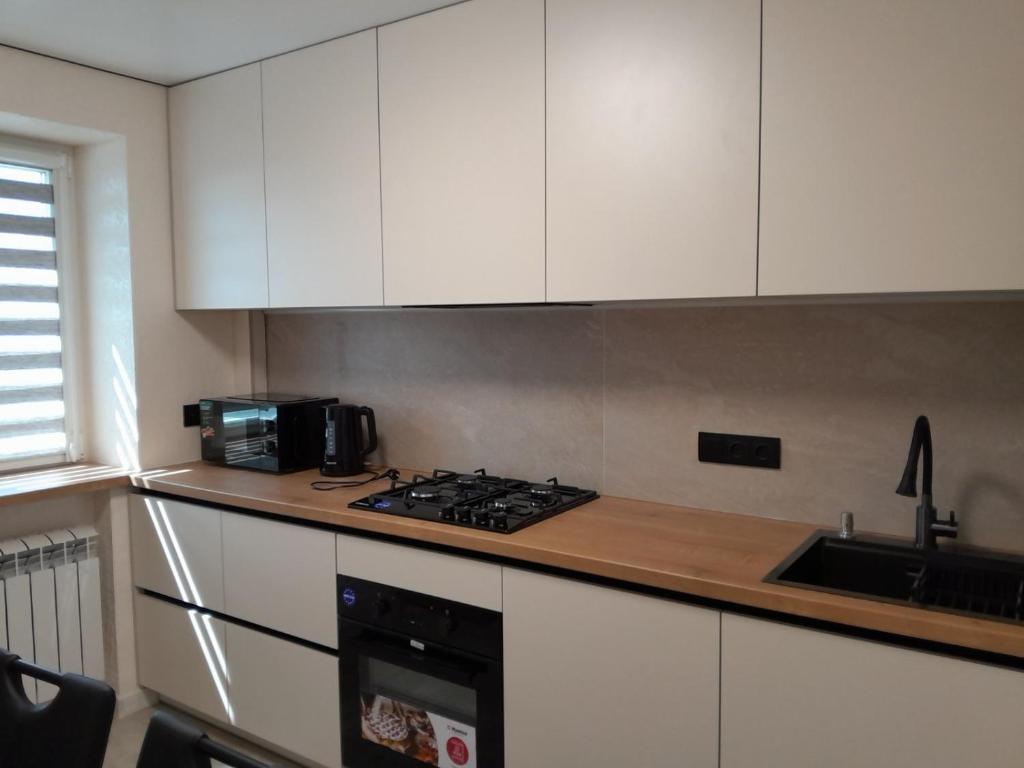 Una cocina con gabinetes blancos y un horno de estufa. en Люкс апартаменты -Центр, en Mykolaiv