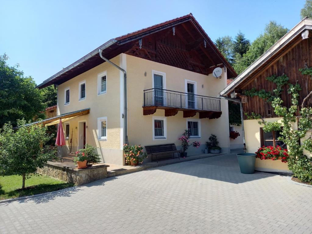 a house with a balcony and a courtyard at Landhof Ella - Ferienhaus vor den Toren Salzburgs in Petting