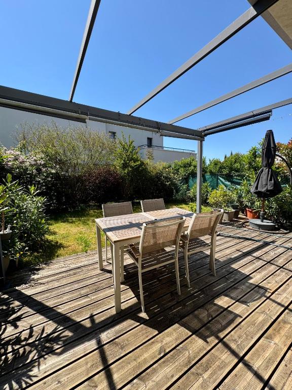 une table et des chaises sur une terrasse en bois dans l'établissement Maison 15 min Disney 30 min Paris, à Ferrières-en-Brie