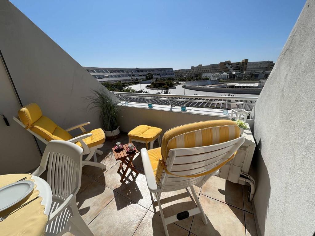 d'un balcon avec des chaises et des tables offrant une vue sur la ville. dans l'établissement Deux pièces CAP D'AGDE NATURISME CN030-209, au Cap d'Agde