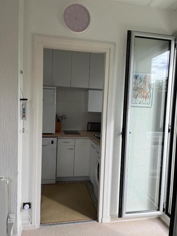 une cuisine avec des placards blancs et une horloge murale dans l'établissement Joli studio - 1ere ligne- Front de mer Royan, à Royan