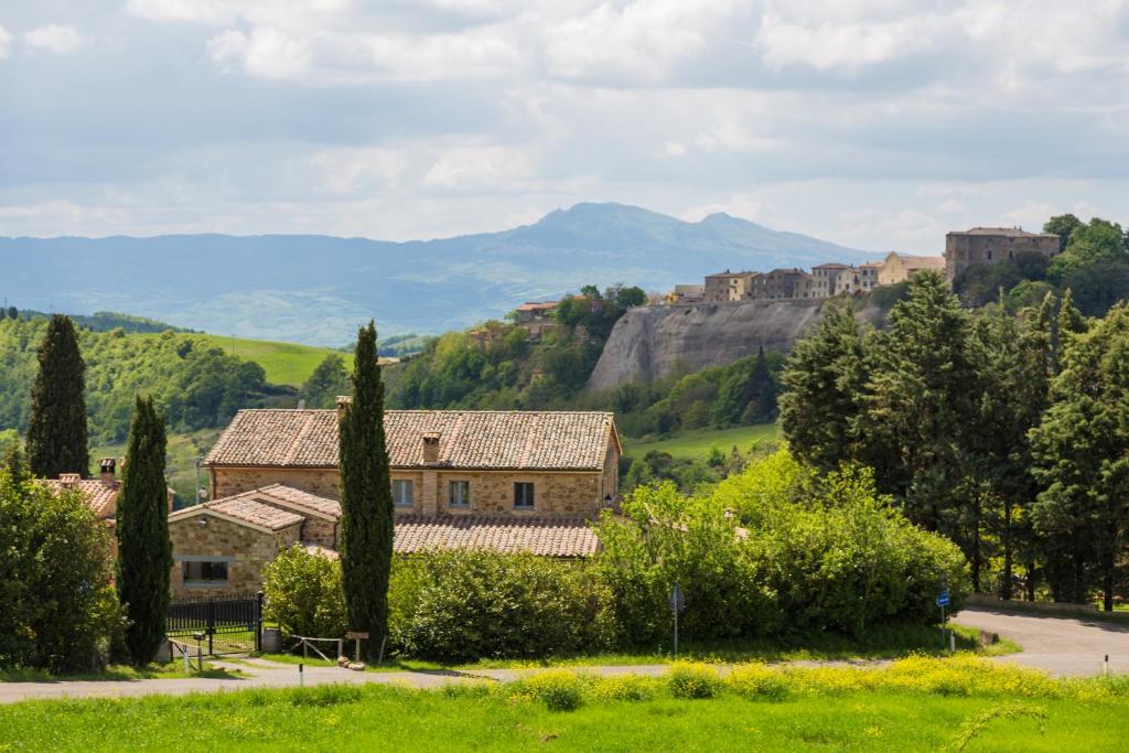 a house in a field with a mountain in the background at Podere Orto Wine Country House in Trevinano
