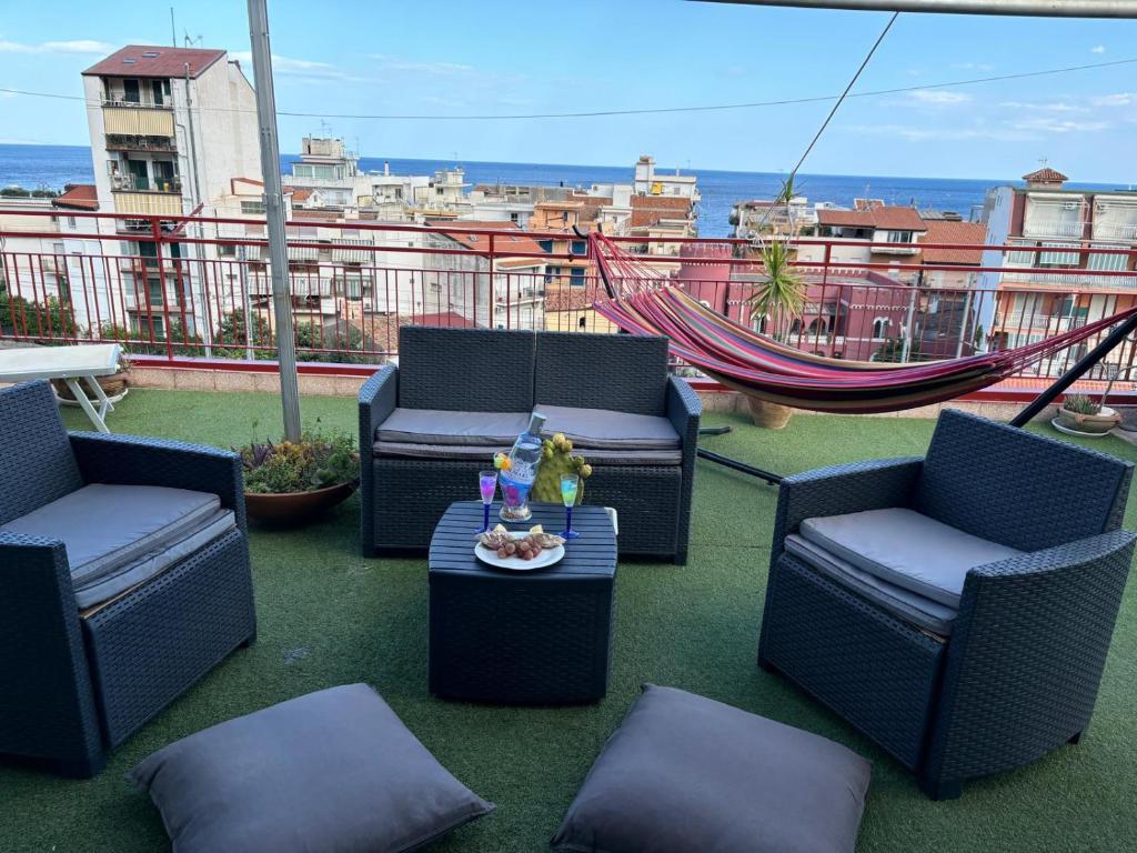 einen Balkon mit Stühlen, einem Tisch und einer Hängematte in der Unterkunft Terrazza Fiumara in Letojanni