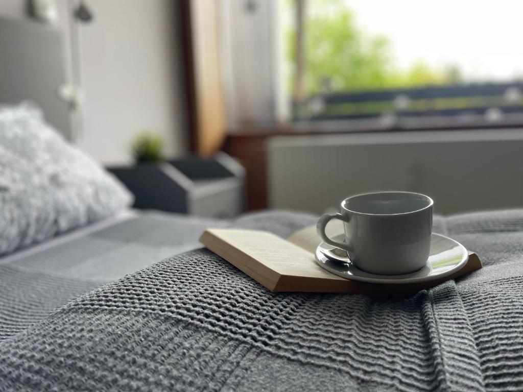 a coffee cup on a plate on a bed at Ferienwohnung in Freudenstadt-Kniebis II in Freudenstadt