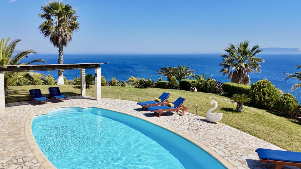 a swimming pool with chairs and a swan and the ocean at Villa Dimitra in Trapezaki