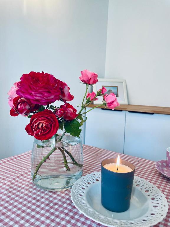 un vase de roses et une bougie sur une table dans l'établissement Z&L Villa Jardin - 2 Chambres 3 Lits - Maison familiale, à Bourg-la-Reine
