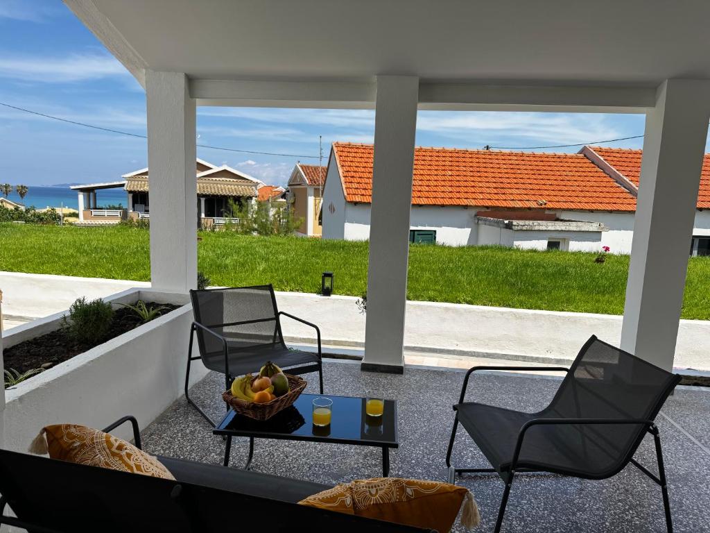 a patio with chairs and a table with a bowl of fruit at Massalia Suites Villa Vita in Agios Stefanos